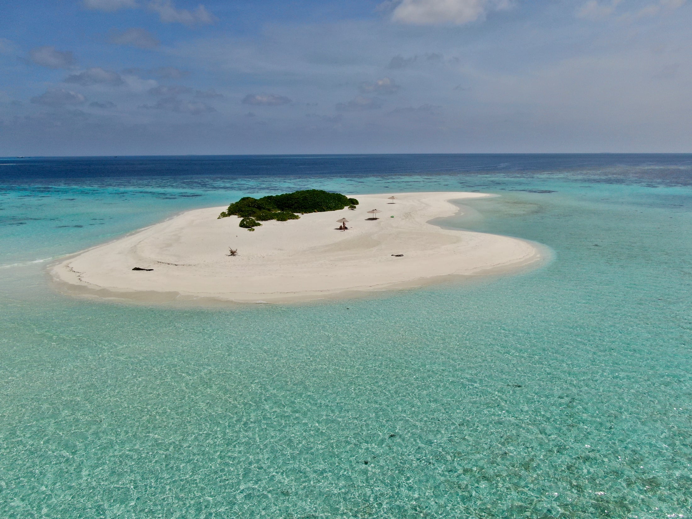 A small uninhabited sandbank in the middle of a turquoise Maldives lagoon