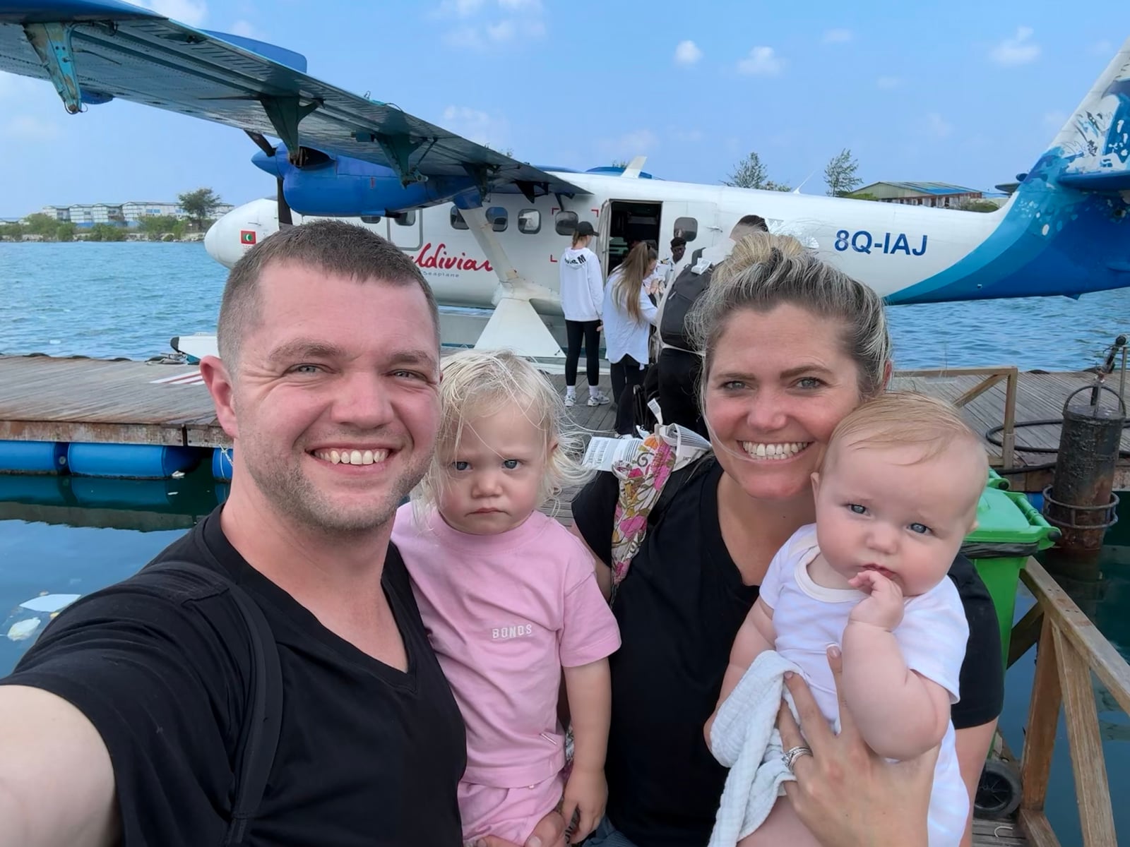 The Lewtak family at a Maldives seaplane dock — Tym, his wife, and their two young daughters
