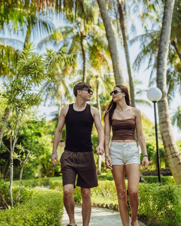 Foto von Adaaran Prestige Water Villas vom 06. Juli 2026. Möglicherweise ein Bild von einer oder mehreren Personen, Menschen, die sich küssen, Sarong, Sommerkleid, Park, Palmen und Text.