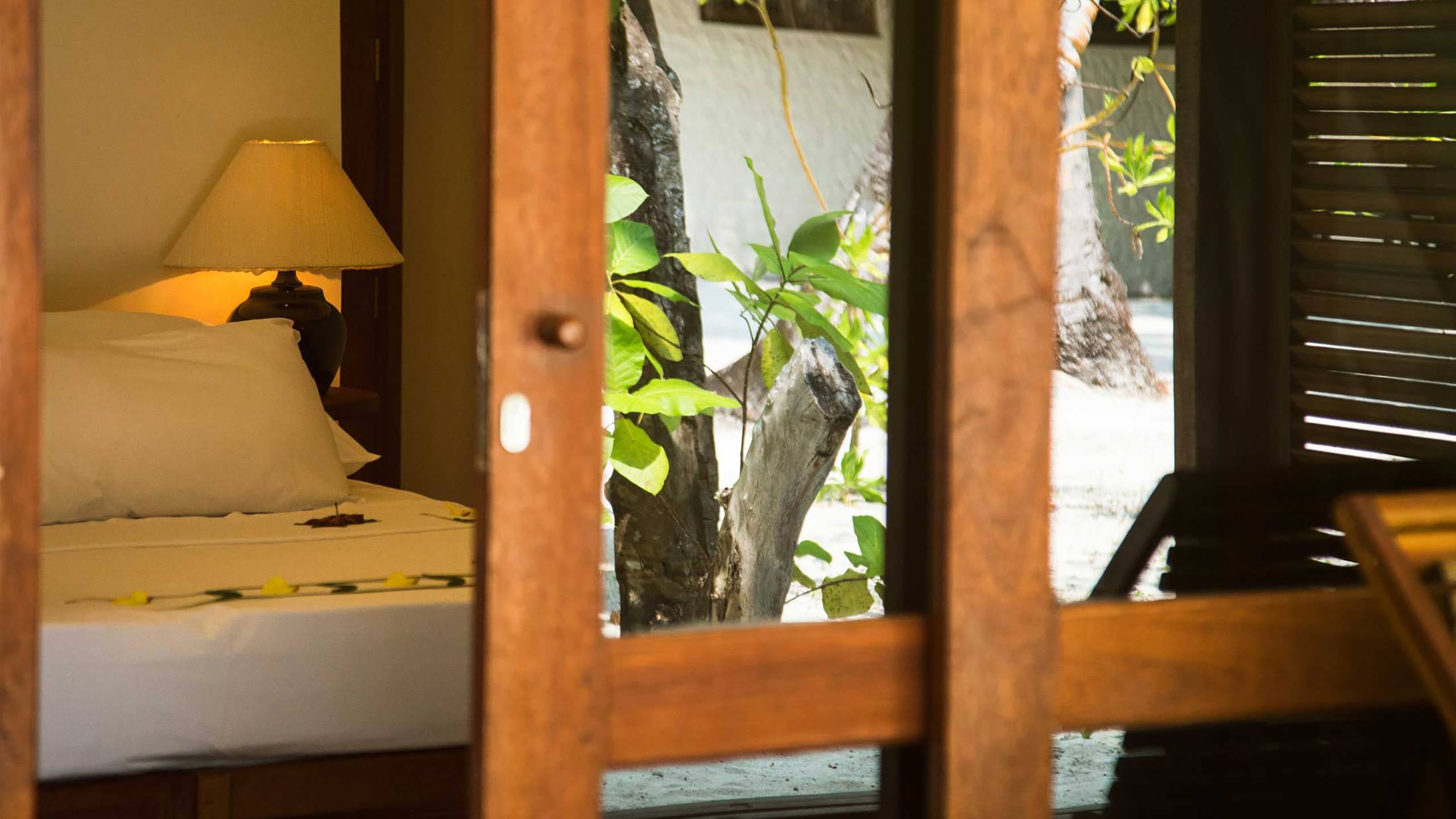 Garden Villa im Alimatha Aquatic Resort, beschattet von hoher Vegetation mit privatem Terrassengarten