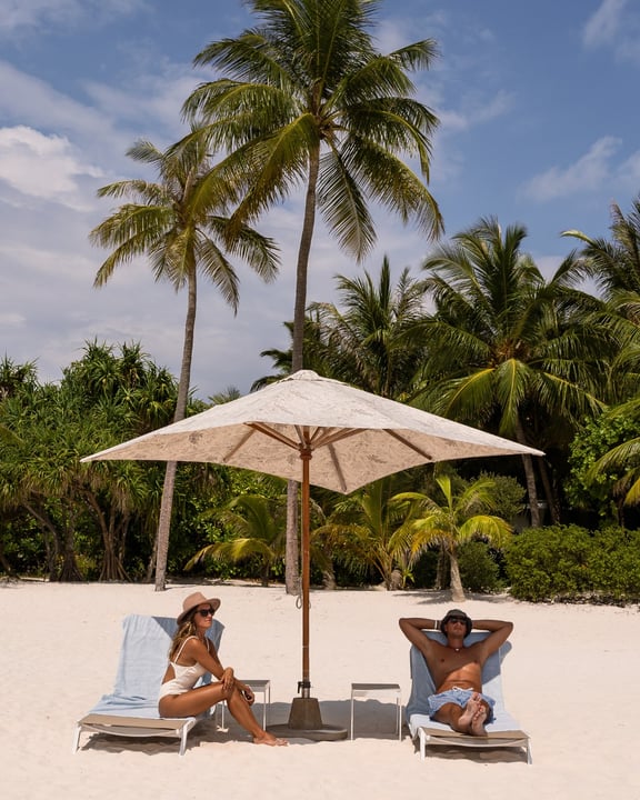 Foto von Amilla Maldives vom 21. Juli 2026. Könnte ein Bild von einer oder mehreren Personen, Sonnenschirm, Liegestuhl, Strand, Palmen, Cabana und Text sein.