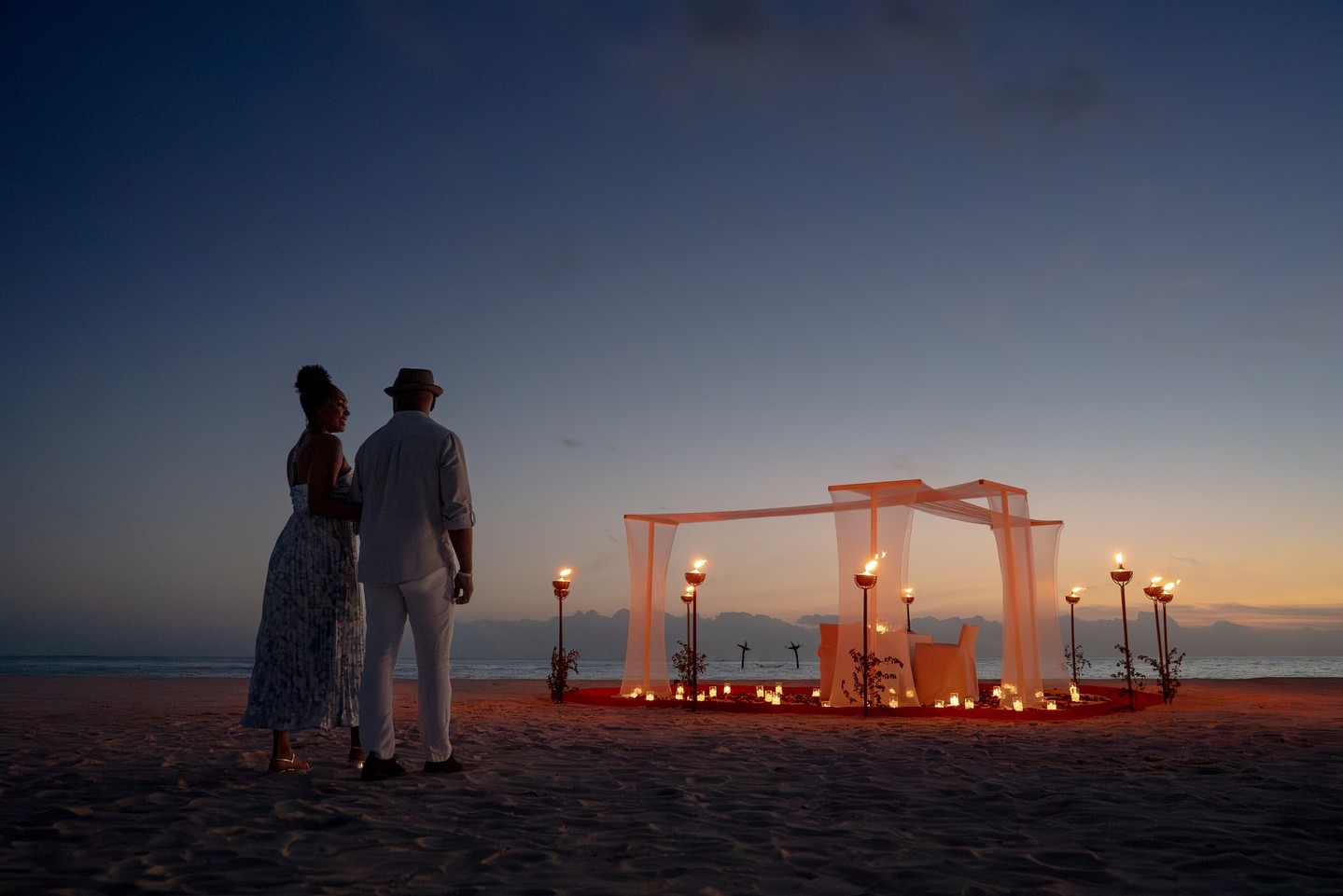Photo by Anantara Dhigu Maldives Resort on June 18, 2026. May be an image of people kissing, candle, lantern, wedding, twilight, outdoors and text.