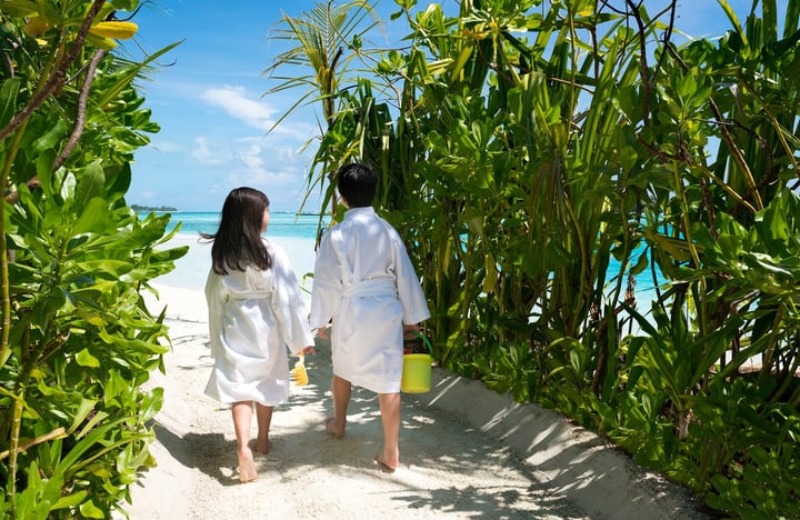 Photo by Anantara Dhigu Maldives Resort on August 11, 2026. May be an image of one or more people, sarong, umbrella, dressing gown, outdoors and text.