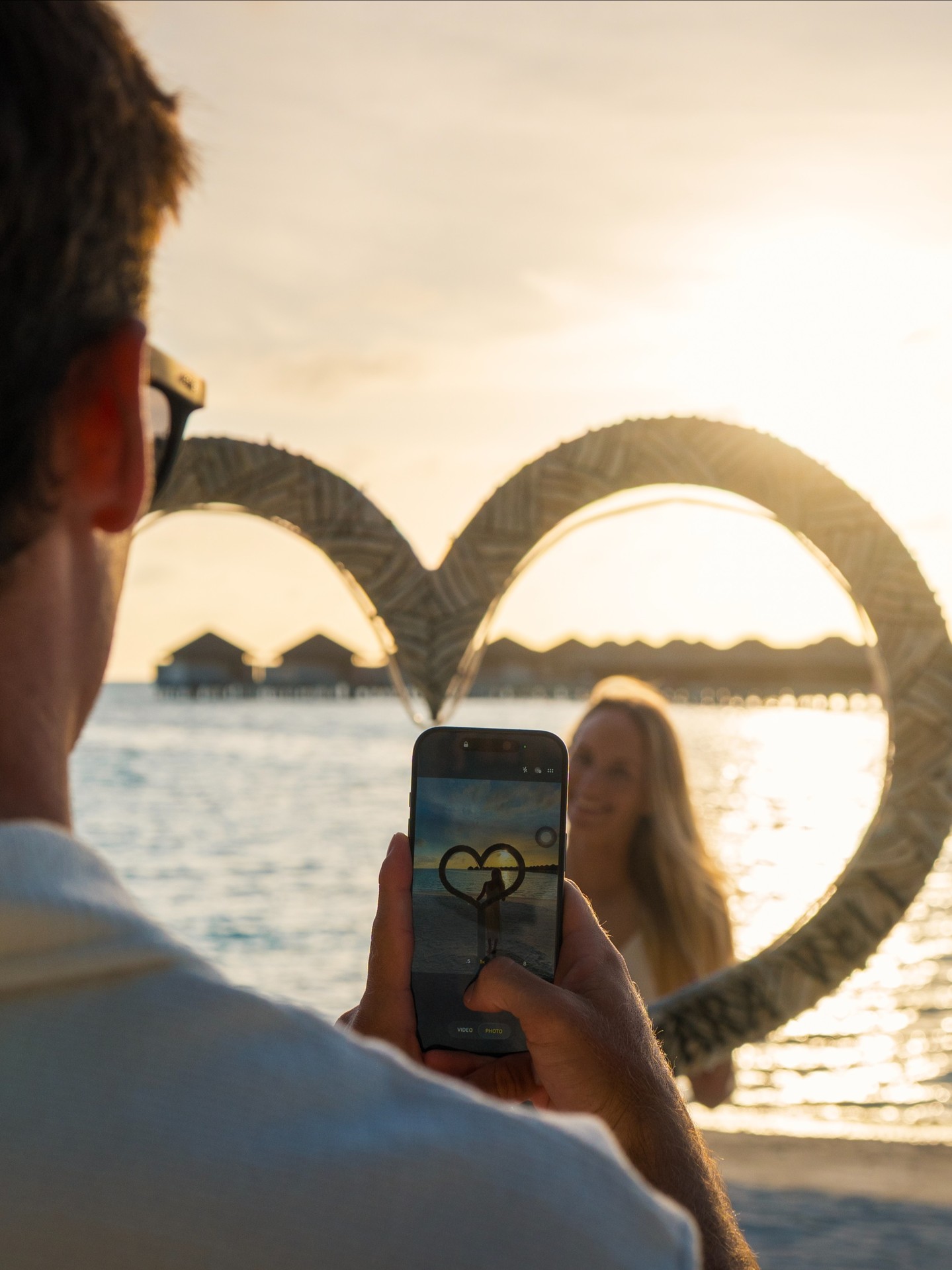 Foto von Anantara Veli Maldives Resort am 26. August 2026. Möglicherweise ein Bild von einer oder mehreren Personen, sich küssenden Personen, Telefon, Wasser und Text.