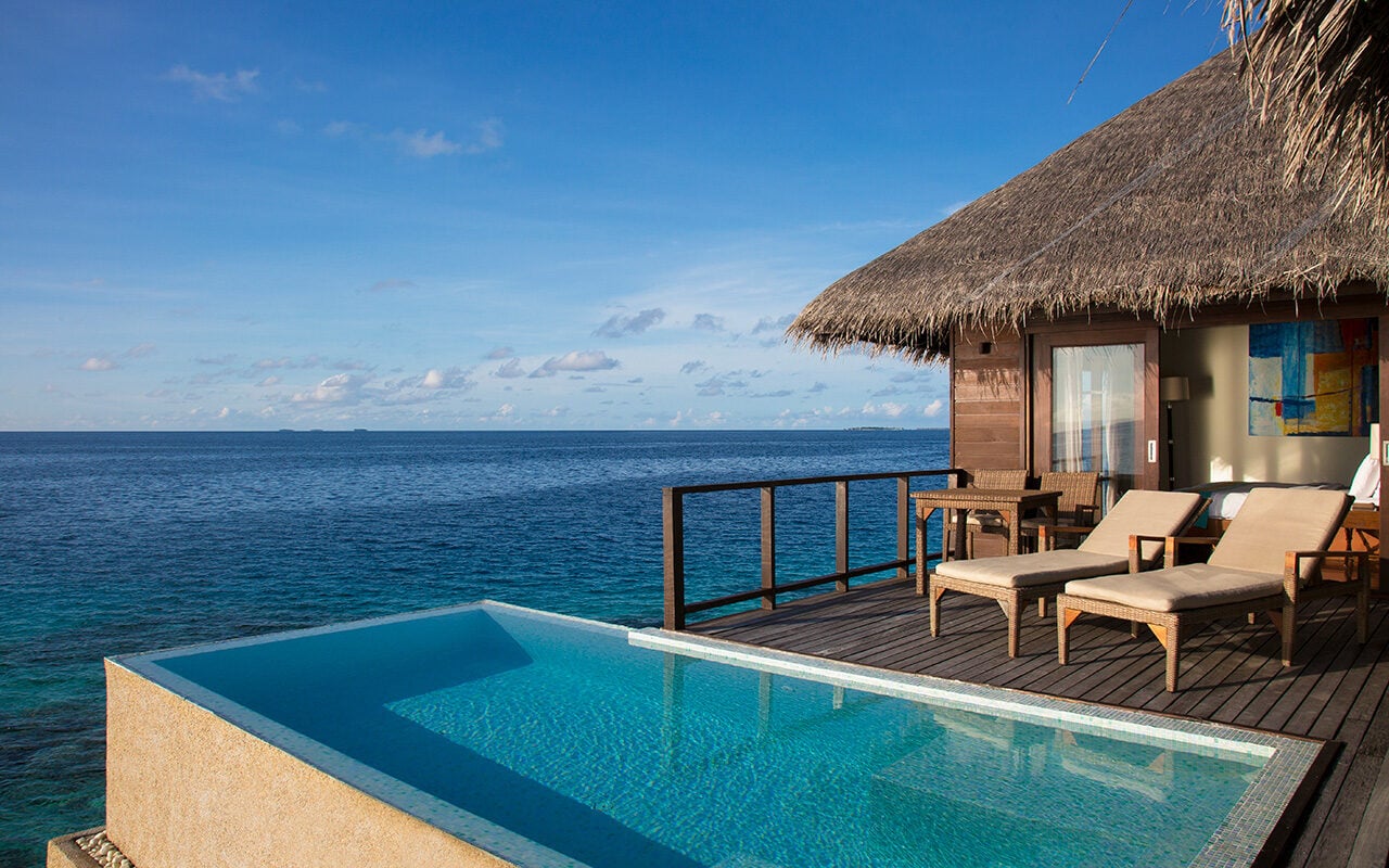 Ein privater Infinity-Pool auf der Terrasse einer Wasservilla blickt bei blauem Himmel auf den Ozean in Coco Bodu Hithi.