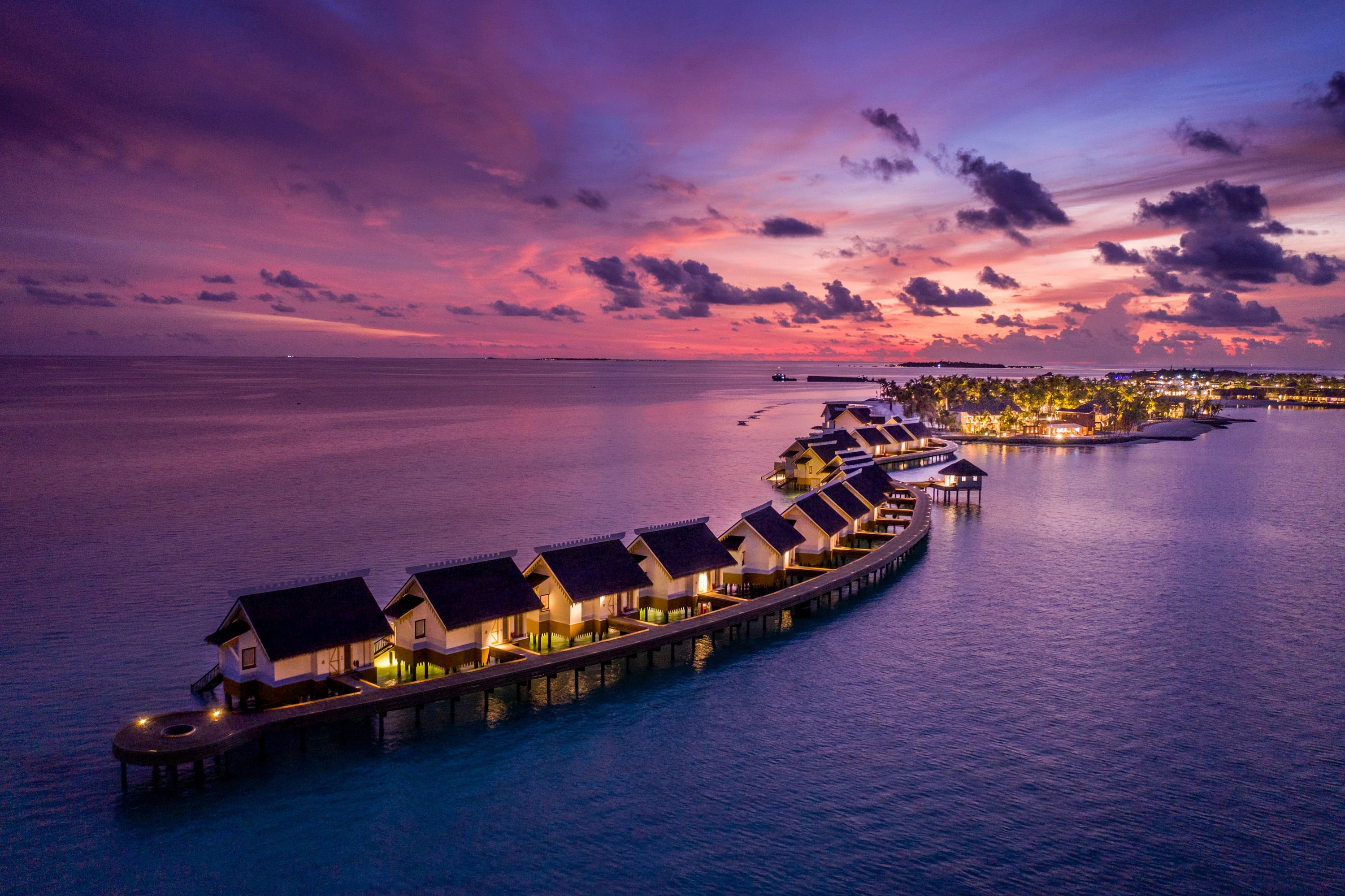 Luftaufnahme einer Wasservilla bei Sonnenuntergang im SAii Lagoon Maldives, Curio Collection by Hilton