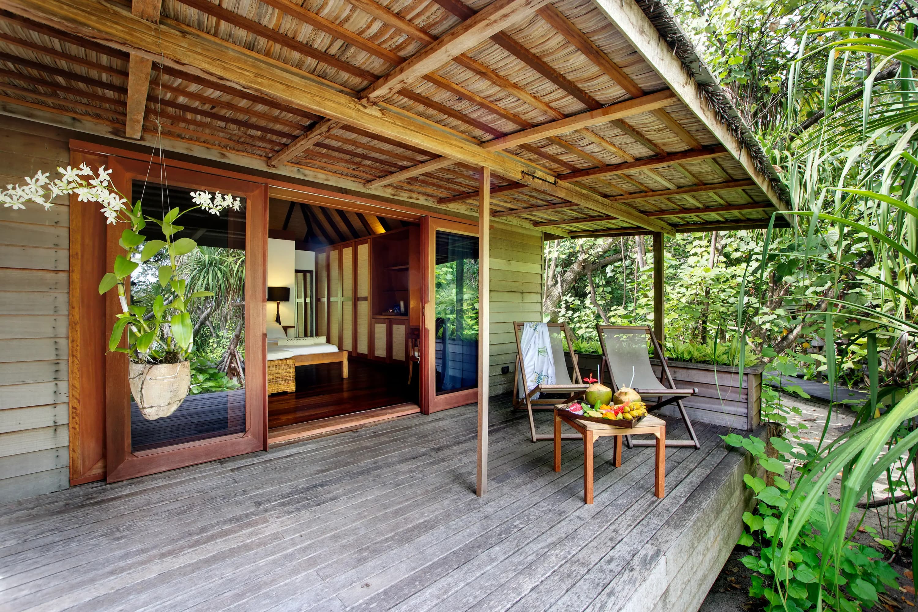Véranda de la Garden Villa, une terrasse en bois avec des chaises longues au milieu de la végétation de l'île à Gangehi Island Resort & Spa