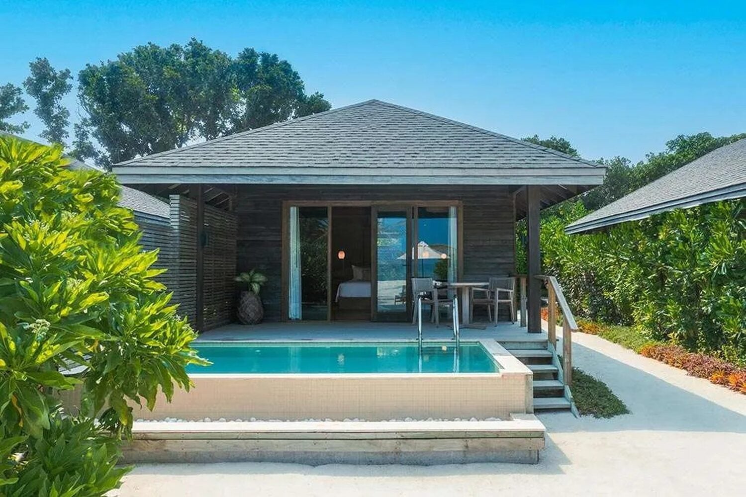 Eine hölzerne Beach Pool Villa mit kleinem privaten Tauchbecken und einem Esstisch im Freien in Jawakara Islands Maldives.