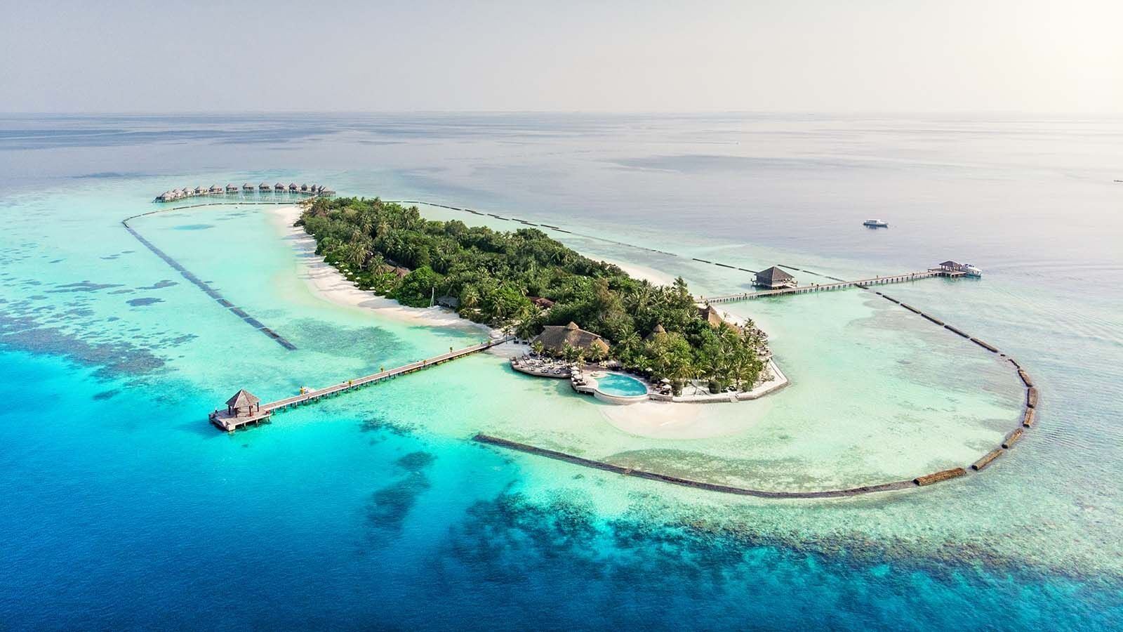 Luftaufnahme von Komandoo Island Resort, umgeben von türkisfarbener Lagune und Wasservillen.