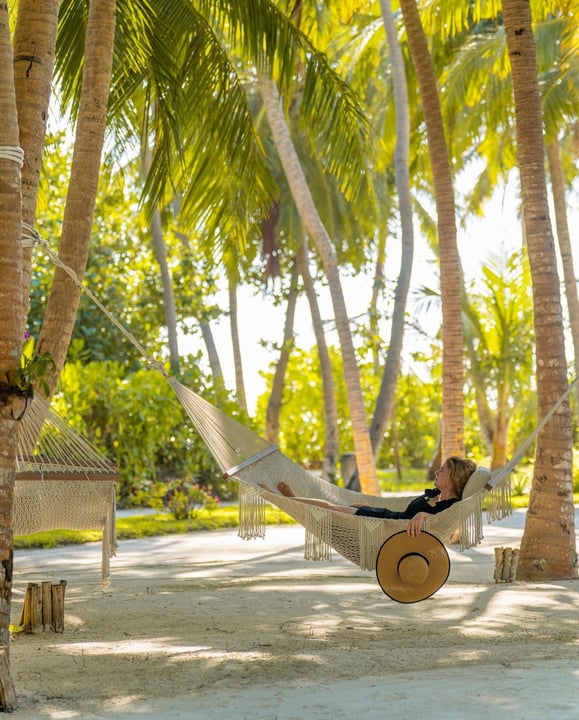 Photo by Kudadoo Maldives in Kudadoo Maldives Private Island. May be an image of deck chair, hammock, chaise longue, outdoors, palm trees and text.