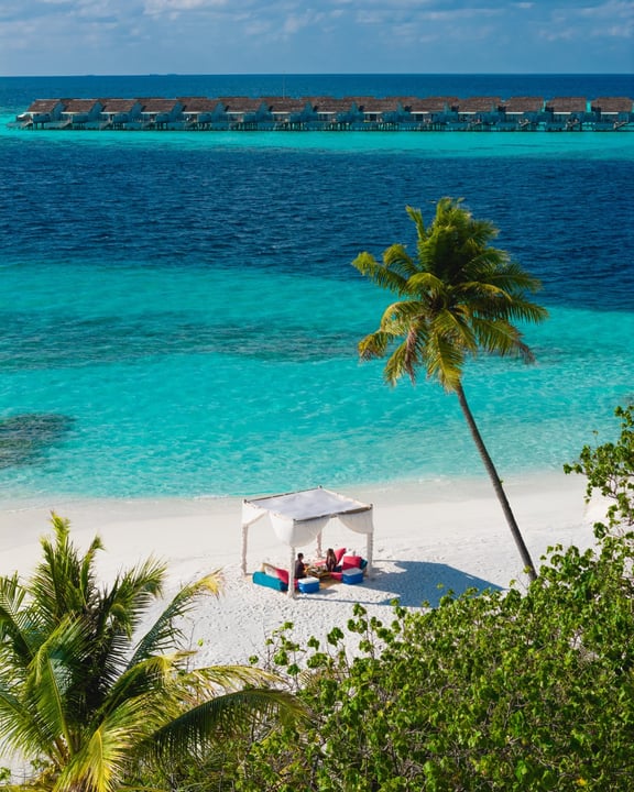 Photo by Outrigger Maldives Maafushivaru on August 08, 2026. May be an image of beach, horizon, ocean, palm trees, cabana and text.