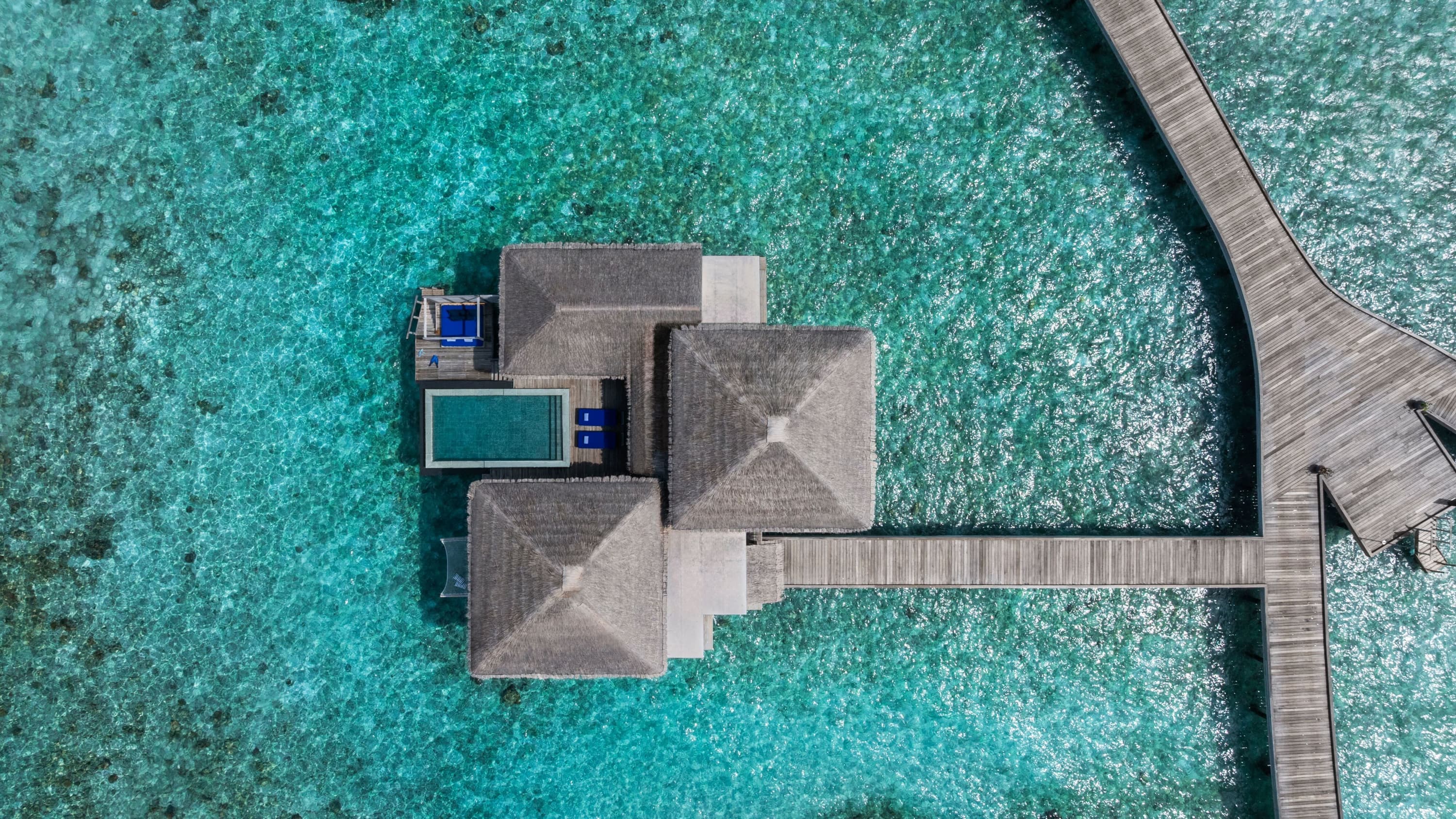 Luftaufnahme der Overwater Pool Villa bei Sonnenuntergang im Raffles Maldives Meradhoo