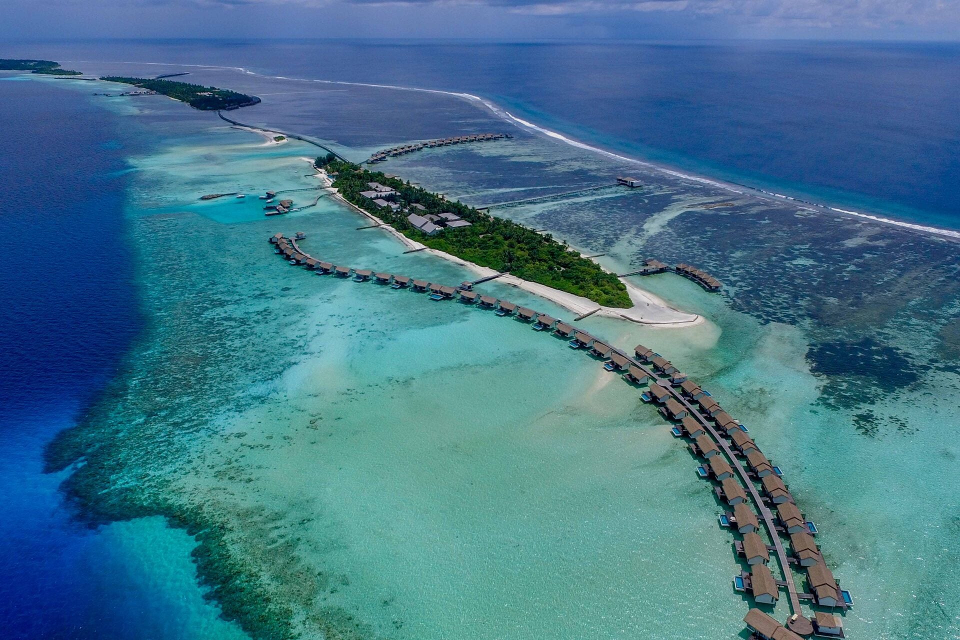 Luftaufnahme der Insel mit ihren geschwungenen Reihen von Wasservillen entlang der Riffkante.