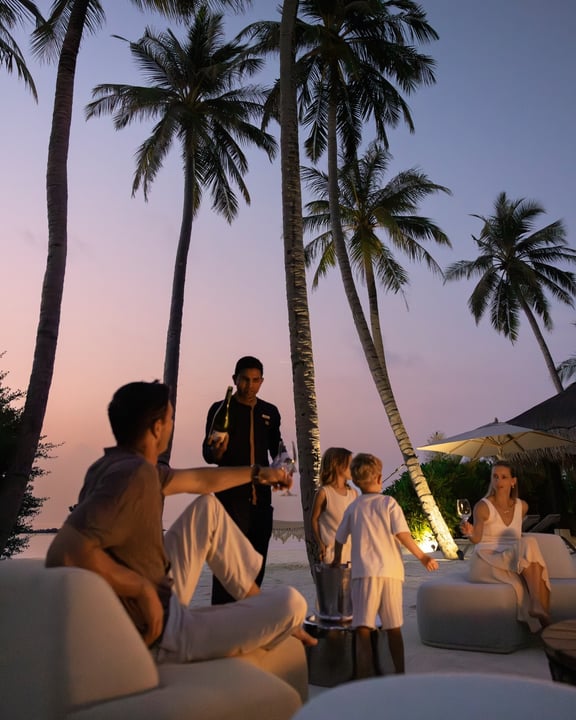 Foto von Velaa Private Island Maldives vom 14. Juli 2026. Zu sehen sind möglicherweise eine oder mehrere Personen, ein Liegestuhl, Dämmerung, im Freien, eine Cabana, Palmen und Text.