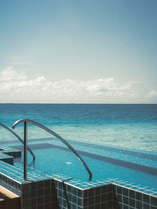 Photo by Niva Velassaru Maldives on June 11, 2026. May be an image of swimming, deck chair, pool, horizon, cabana and text.